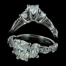 From Durnell's Vintage Lace Collection, a three-stone oval classic engagement ring in platinum.  Delicately scalloped shank, articulated with brilliant diamonds with very feminine appeal.  Pave diamond eternity bands fit flush on either side and look fabulous.  Also available in stackables.