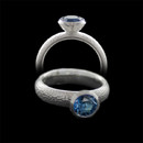 Sterling silver ring by Bastian Inverun. The ring is bezel set with a round London blue topaz. The ring features a brushed and hammered finish shank measuring approximately 4.5mm in width.