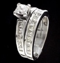 A very fine 14k white gold diamond wedding set. The rings are soldiered together but can be sized and separated. 
The ring is set with a 4.7mm x 4.5mm ( .65CT) Princess cut diamond we grade SI1 H-I Very good cut grade. (grading is tight on this) The e-ring and band are set with 15 Princess cut diamonds that range from SI1 to VS, G-I color and very well cut and matched. Approximately total weight of 2.05ct. 
The rings measure 8mm total, 4 mm each at the top and tapers. 
The rings weight is total 6.8 grams and a size 6. Very fine condition with very little wear. 
You'll like this and it's made in America.