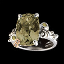 A sterling silver ring with smokey quartz center stone and two citrine side stones. The center smokey quartz has a total carat weight of 6.40 and the two side citrine are 0.10tcw. The signature "B"  is made of 18K gold and has a total carat weight of 0.01tcw.